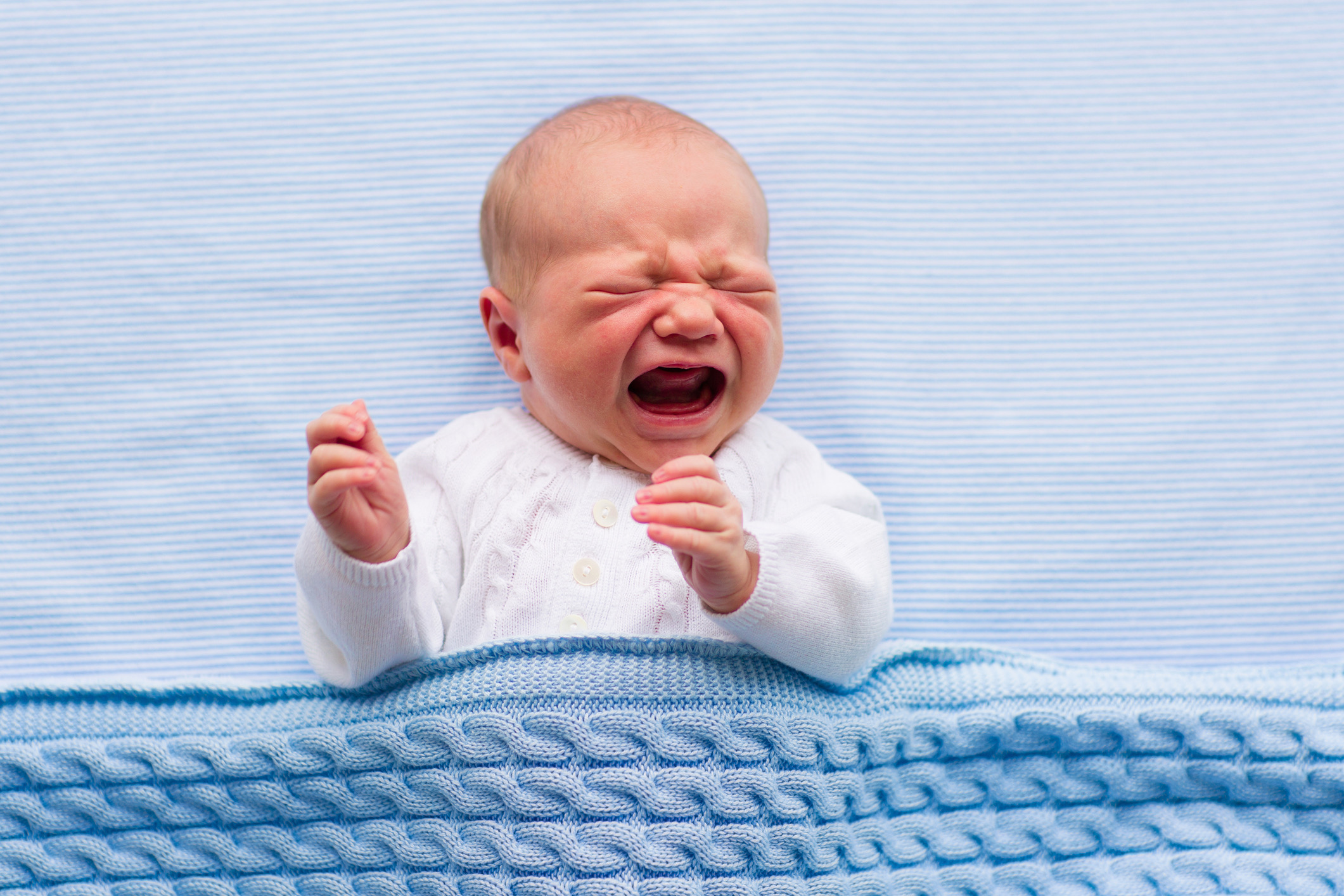 Newborn baby boy on a blue blanket crying