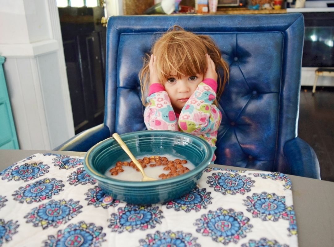 Toddle sat on a blue chair with a bowl of cereal having a Toddler Tantrums at the Table