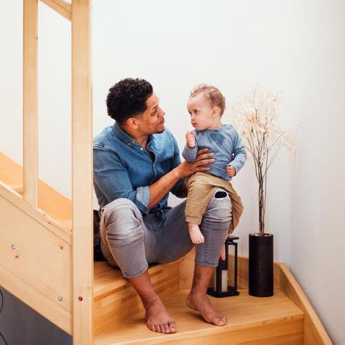 Toddler Sat On Dad's Knee on the stairs