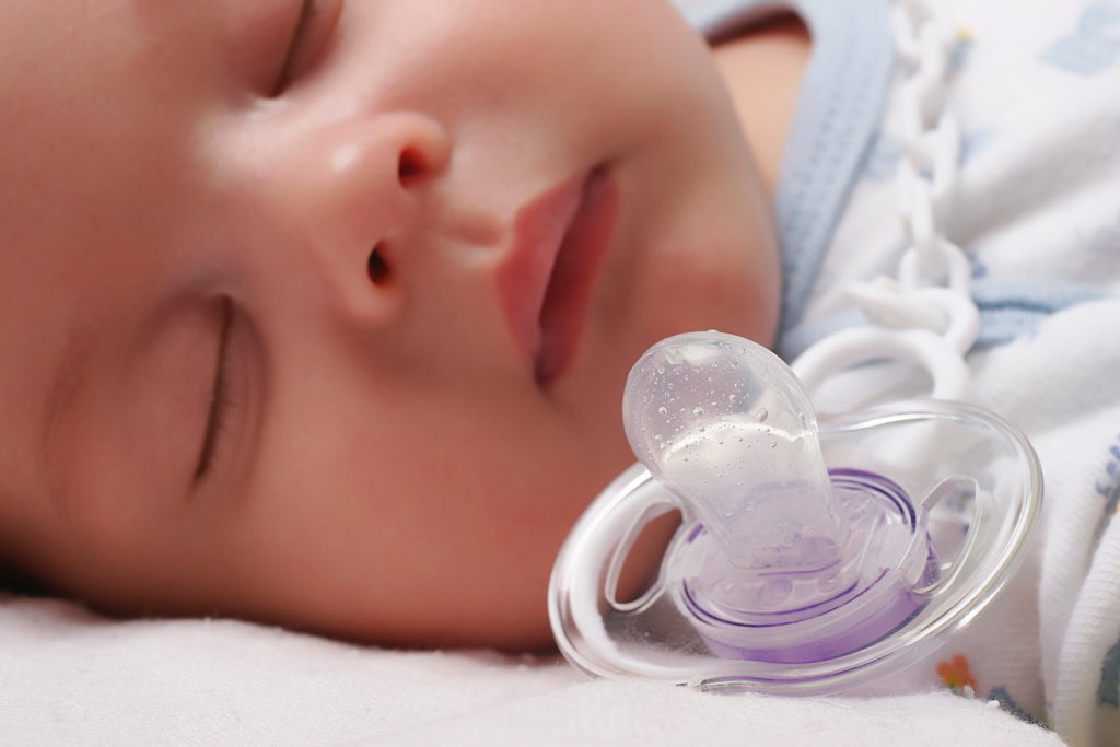 Baby sleeping by a dummy