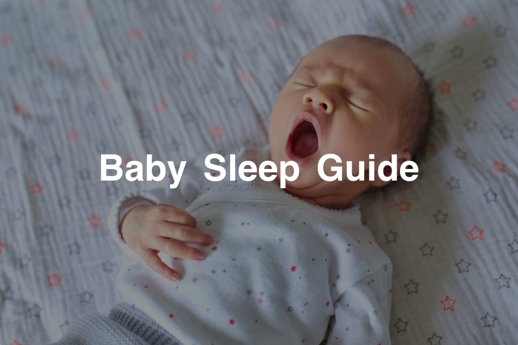 Yawning baby in cot with eyes closed
