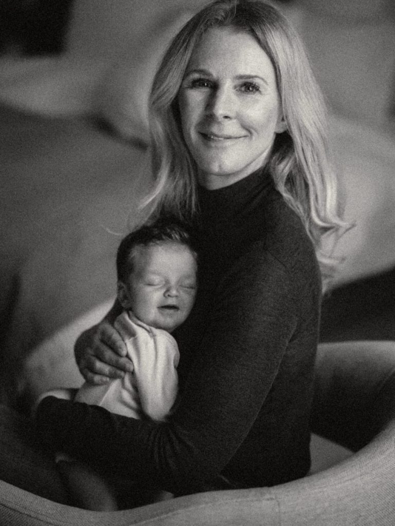 Charmian Mead a parent and baby sleep coach holding a smiling baby with it's eyes closed